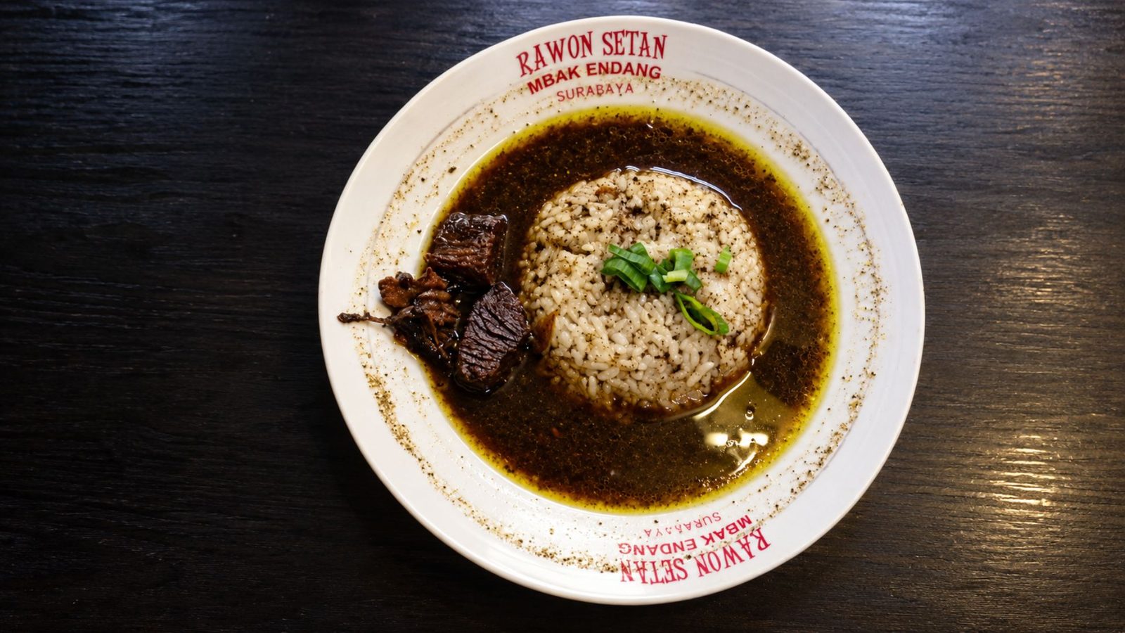 Detail kuah rawon hitam pekat dengan sambal di sisi mangkuk